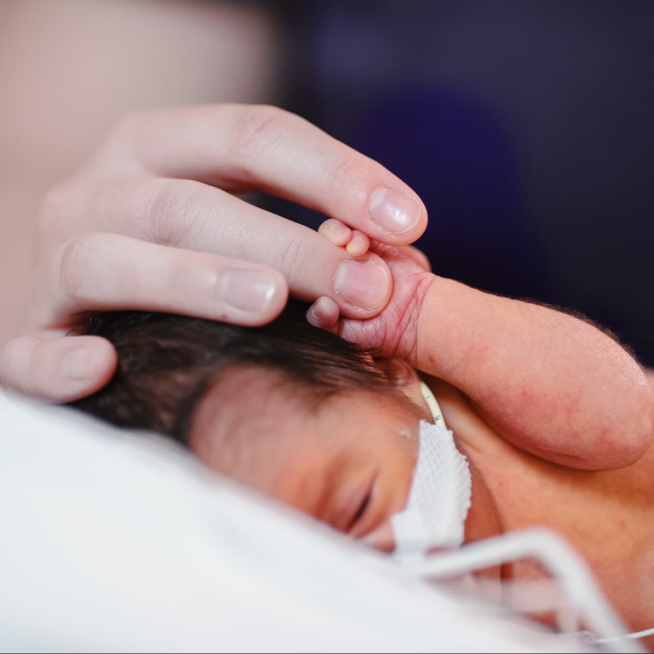 Children's provider holding infant's hand in the hospital.