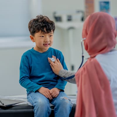 Provider listening to young patient's heart.