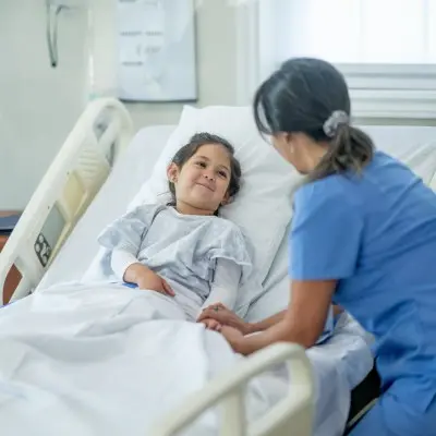 Nurse holding young patient's hand.
