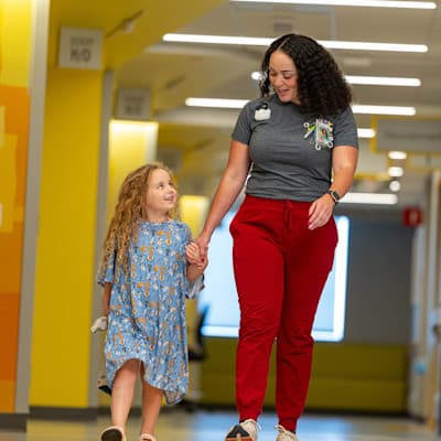 Nurse walking with young patient through hallway of Children's Nebraska hospital.