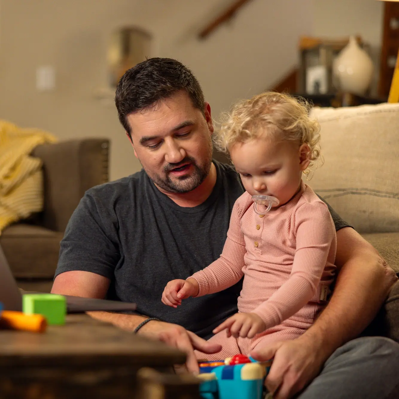 Father at home playing with young child.