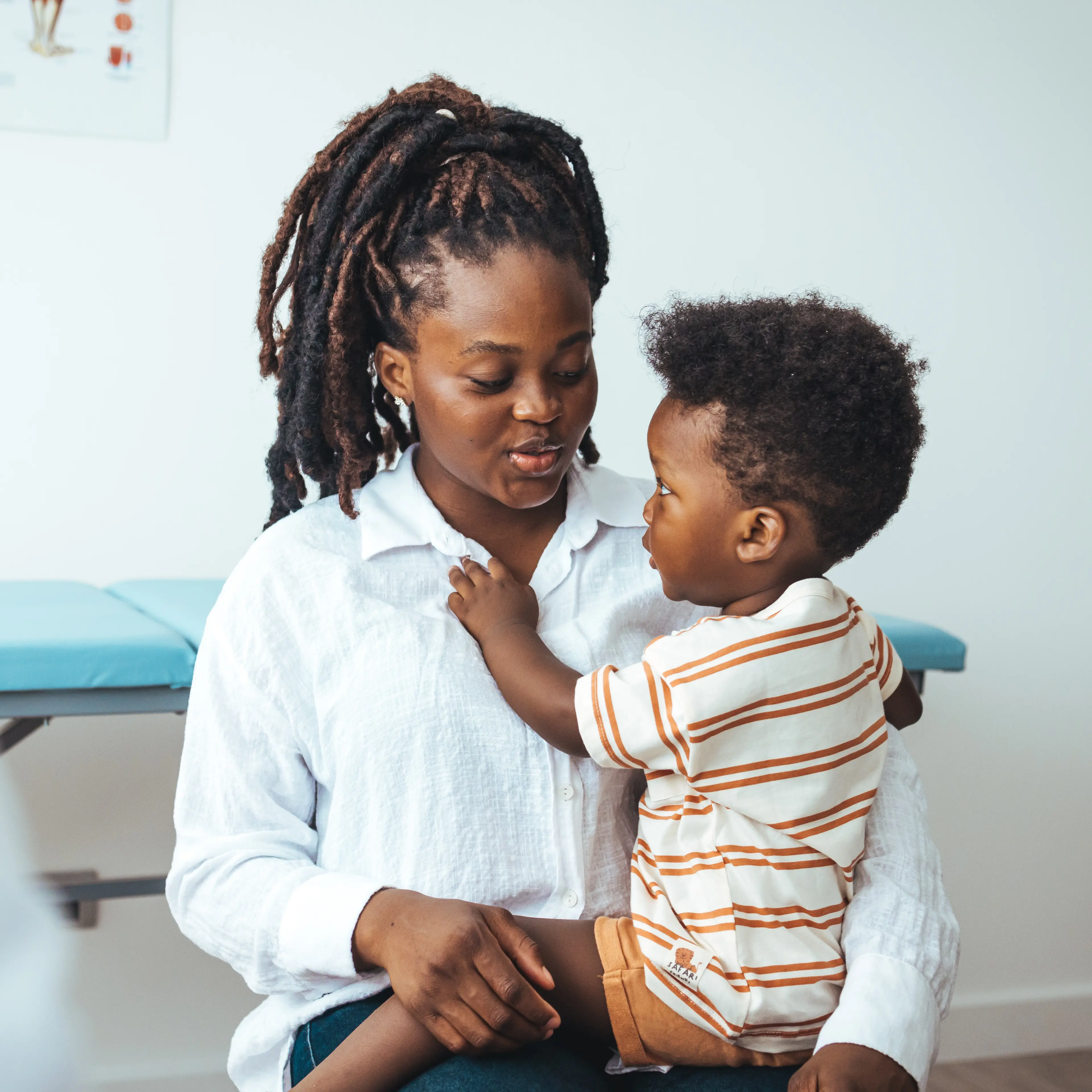 Mother holding son while visiting with a pediatric specialist.
