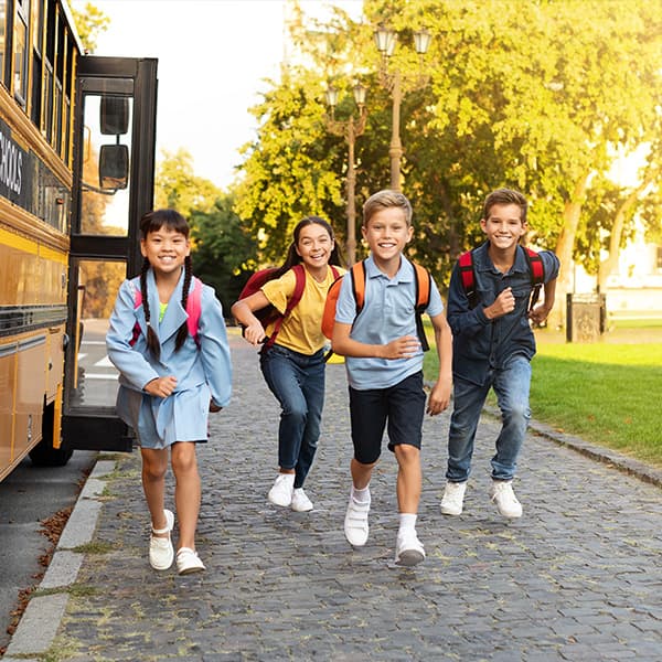 Kids running by a school bus