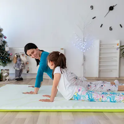 Mother and daughter doing yoga together in the living room.
