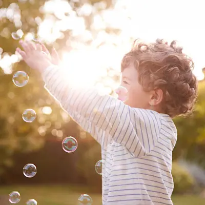 Happy boy playing outside with bubbles.
