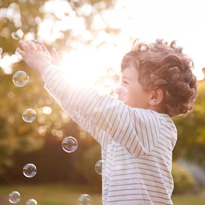 Happy boy playing outside with bubbles.