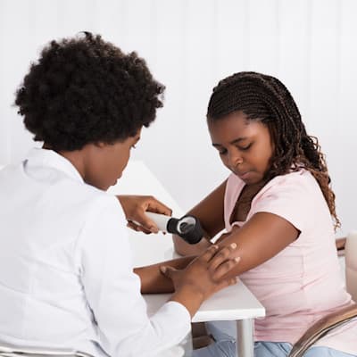 Dermatologist examining teen's skin.