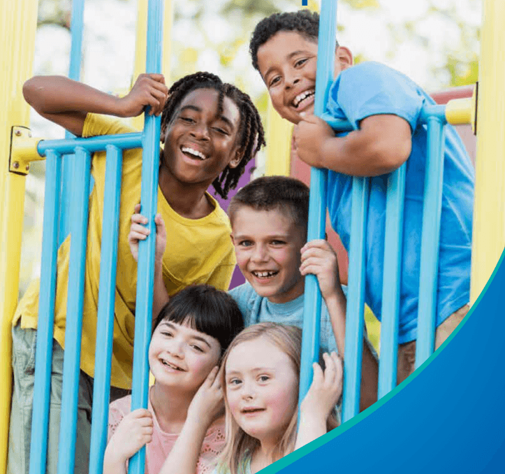 Five smiling children of diverse backgrounds playing together on a colorful blue and yellow playground structure outdoors.