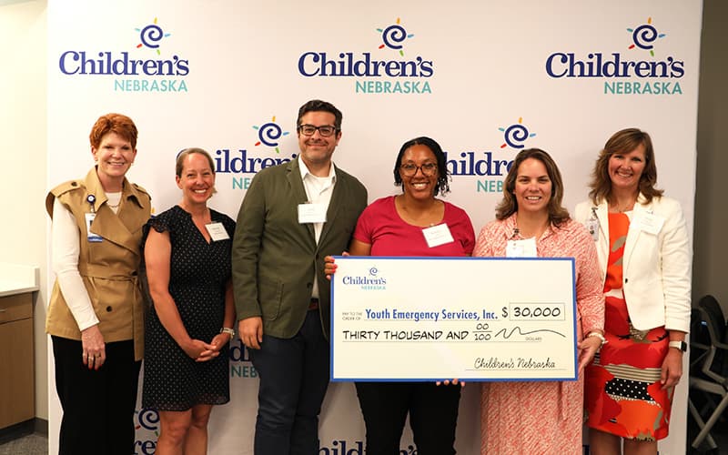 Youth Emergency Services (YES) and Children's Nebraska representatives hold a large check for $30,000.
