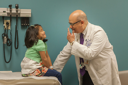 physician points to nose during office visit with young female patient